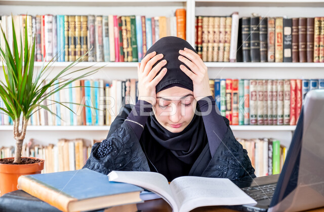 Integrating modern technologies into academic education, curricula and educational materials in Saudi colleges, the concept of diligence and excellence, a young Saudi Arabian Gulf woman putting her hand on her head with gestures of fatigue and exhaustion, remote electronic university lectures, reviewing daily lessons via laptop