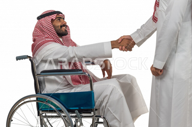 بورتريه لرجل عربي سعودي خليجي من ذوي الهمم يجلس على كرسي متحرك يصافح صديقه, التمكين الاجتماعي, اهتمام  ودعم المجتمع السعودي لذوي الاحتياجات الخاصه, شعور ذوي الهمم بالراحه والطمأنينه في بيئتهم