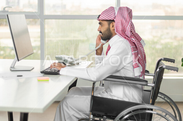 موظف عربي سعودي خليجي من ذوي الهمم يعمل على جهاز الحاسوب في مقر العمل, دمج و توظيف ذوي الاعاقه في مختلف المجالات, التمكين الاجتماعي, اهتمام  ودعم المجتمع السعودي لذوي الاحتياجات الخاصه, شعور ذوي الهمم بالراحه والطمأنينه في بيئتهم