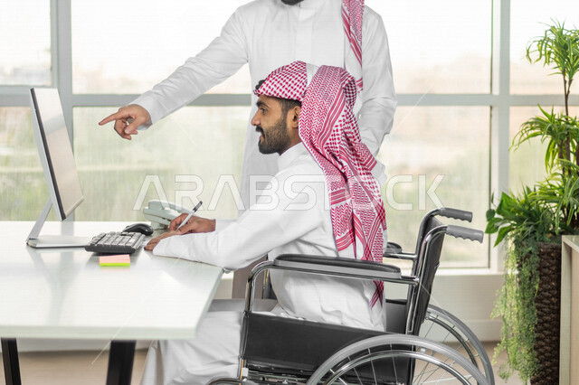 موظف عربي سعودي خليجي من ذوي الهمم يعمل على جهاز الحاسوب في مقر العمل, دمج و توظيف ذوي الاعاقه في مختلف المجالات, التمكين الاجتماعي, اهتمام  ودعم المجتمع السعودي لذوي الاحتياجات الخاصه, شعور ذوي الهمم بالراحه والطمأنينه في بيئتهم