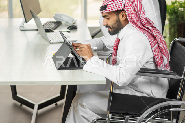 موظف عربي سعودي خليجي من ذوي الهمم يعمل على جهاز التابلت في مقر العمل, دمج و توظيف ذوي الاعاقه في مختلف المجالات, التمكين الاجتماعي, اهتمام  ودعم المجتمع السعودي لذوي الاحتياجات الخاصه, شعور ذوي الهمم بالراحه والطمأنينه في بيئتهم