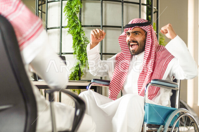 موظف عربي سعودي خليجي من ذوي الهمم  في مقر العمل, دمج و توظيف ذوي الاعاقه في مختلف المجالات, التمكين الاجتماعي, اهتمام  ودعم المجتمع السعودي لذوي الاحتياجات الخاصه, ايماءات وتعابير وجه ويدين تدل على الفوز والنجاح