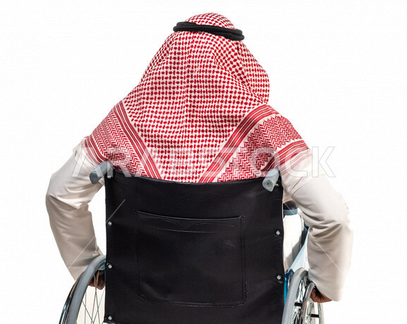 بورتريه من الخلف لرجل عربي سعودي خليجي من ذوي الهمم يجلس على كرسي متحرك, التمكين الاجتماعي, اهتمام  ودعم المجتمع السعودي لذوي الاحتياجات الخاصه, شعور ذوي الهمم بالراحه والطمأنينه في بيئتهم