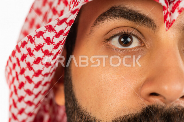 بورتريه بصورة مقربة لرجل سعودي خليجي يقوم بجلسة تصوير ، ينظر لأعلى ، خلفية بيضاء لرجل سعودي مسلم يرتدي الزي التقليدي السعودي مع شماغ وعقال
