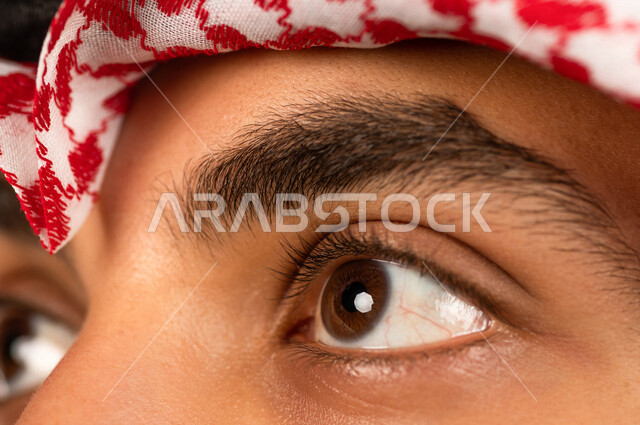 بورتريه بصورة مقربة لرجل سعودي خليجي يقوم بجلسة تصوير ، ينظر لأعلى ، خلفية بيضاء لرجل سعودي مسلم يرتدي الزي التقليدي السعودي مع شماغ وعقال