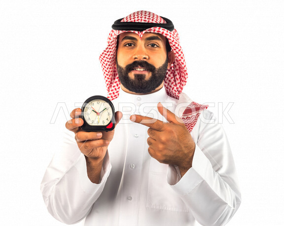 بورتريه لرجل سعودي خليجي يحمل ساعة رقمية صغيرة بإيماءات وجه ويدين مختلفة ، خلفية بيضاء لرجل سعودي يرتدي الزي التقليدي السعودي مع شماغ وعقال ، مفهوم إدارة وقت العمل ، الدقة في المواعيد ، التذكيرات والتنبيهات الثابته ، مواعيد العمل ، إنجاز المهامات في الوقت