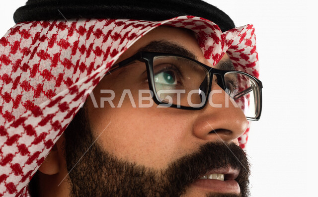 صورة مقربة لرجل سعودي خليجي يقوم يرتدي نظارات طبية وينظر لأعلى، خلفية بيضاء