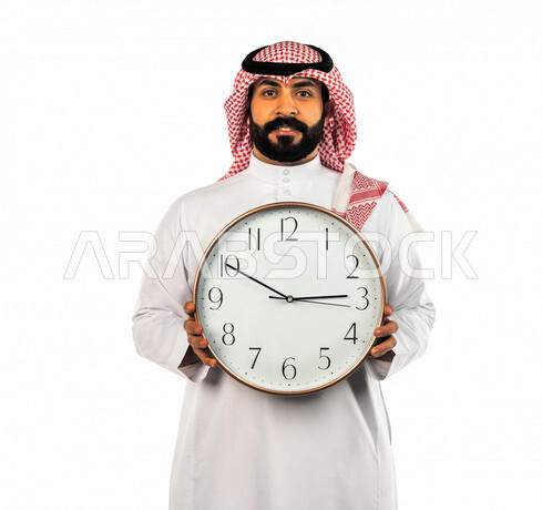 بورتريه لرجل سعودي خليجي يحمل ساعة رقمية كبيرة بإيماءات وجه ويدين مختلفة ، خلفية بيضاء لرجل سعودي يرتدي الزي التقليدي السعودي مع شماغ وعقال ، مفهوم العد التنازلي ، الدقة في المواعيد ، التذكيرات والتنبيهات الثابته ، مواعيد العمل ، إنجاز المهامات في الوقت