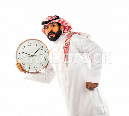 بورتريه لرجل سعودي خليجي يحمل ساعة رقمية كبيرة بإيماءات وجه ويدين مختلفة ، خلفية بيضاء لرجل سعودي يرتدي الزي التقليدي السعودي مع شماغ وعقال ، مفهوم العد التنازلي ، الدقة في المواعيد ، التذكيرات والتنبيهات الثابته ، مواعيد العمل ، إنجاز المهامات في الوقت