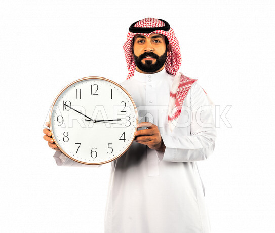 بورتريه لرجل سعودي خليجي يحمل ساعة رقمية كبيرة بإيماءات وجه ويدين مختلفة ، خلفية بيضاء لرجل سعودي يرتدي الزي التقليدي السعودي مع شماغ وعقال ، مفهوم العد التنازلي ، الدقة في المواعيد ، التذكيرات والتنبيهات الثابته ، مواعيد العمل ، إنجاز المهامات في الوقت