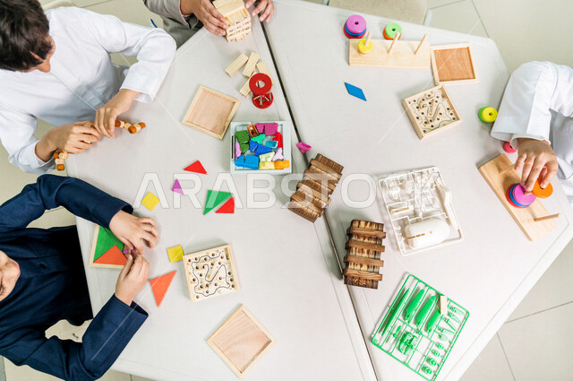 صورة مقربة لمجموعة من التلاميذ العرب الخليجيين السعوديين يجلسون على المكتب الدراسي وامامهم مجموعة من الالعاب، فصل الفنون، العاب وادوات فنية، التعليم في المملكة العربية السعودية