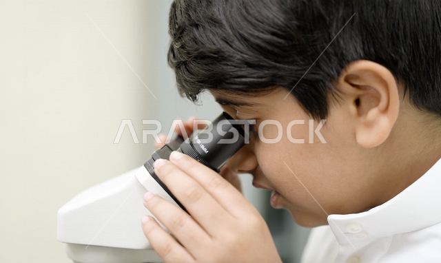 تلميذ عربي خليجي سعودي يرتدي الزي المدرسي، اجراء البحوثات والاختبارات باستخدم التلسكوب داخل مختبر المدرسة، بحوث علمية، التعليم في المملكة العربية السعودية