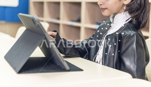 تلميذة عربية خليجية سعودية، متابعة الدروس والواجبات عبر الانترنت، استخدام جهاز التابلت، التعليم الالكتروني ، التعلم عن بعد، التعليم في المملكة العربية السعودية