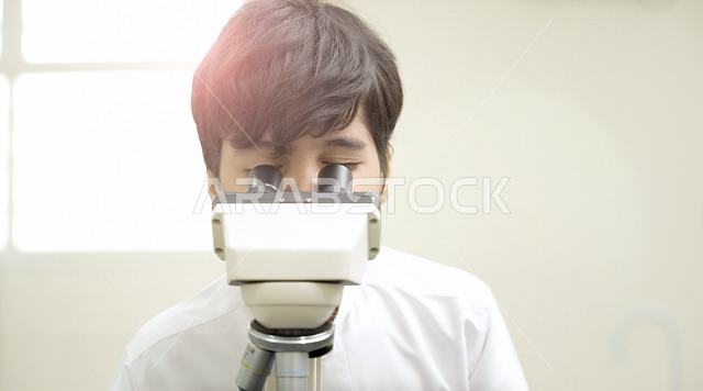 تلميذ عربي خليجي سعودي يرتدي الزي المدرسي، اجراء البحوثات والاختبارات باستخدم التلسكوب داخل مختبر المدرسة، بحوث علمية، التعليم في المملكة العربية السعودية