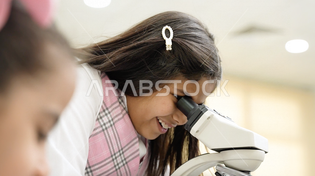 تلميذة عربية خليجية سعودية ترتدي الزي المدرسي، اجراء البحوثات والاختبارات باستخدم التلسكوب داخل مختبر المدرسة، بحوث علمية، التعليم في المملكة العربية السعودية