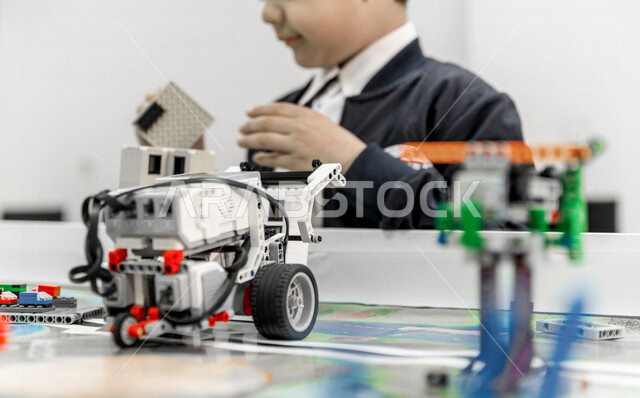 A Saudi Arabian Gulf student, installing and operating a robot car, conducting scientific experiments inside the school laboratory, scientific research, education in the Kingdom of Saudi Arabia.