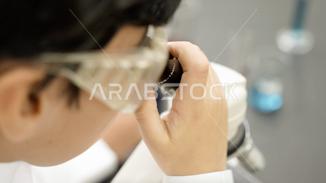 تلميذ عربي خليجي سعودي يرتدي الزي المدرسي، اجراء البحوثات والاختبارات باستخدم التلسكوب داخل مختبر المدرسة، بحوث علمية، التعليم في المملكة العربية السعودية