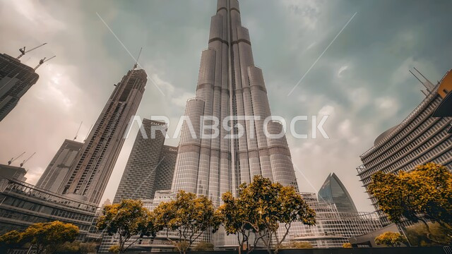 الفن الهندسي المعماري للأبراج وناطحات السحاب، جذب واستقطاب السياح من انحاء العالم، أماكن ومعالم سياحية مشهورة، منظر السماء المليئة بالغيوم، التطور والتقدم العمراني في الامارات العربية المتحدة، صورة من الأسفل لبرج خليفة الشهير في مدينة دبي
