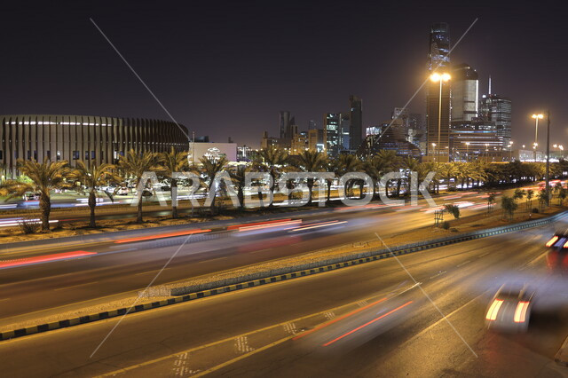 صورة لطريق سريع لمركز الملك عبدالله المالي (كافد) في الرياض بالمملكة العربية السعودية ، أبراج مدينة الرياض ، السياحة في السعودية ، حركة سير السيارات على الطريق العام في وضع الليل ، لقطة مسائية لمعالم الرياض