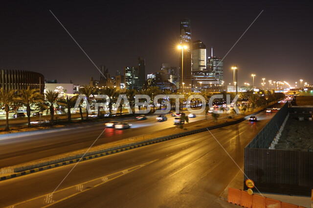 صورة لطريق سريع لمركز الملك عبدالله المالي (كافد) في الرياض بالمملكة العربية السعودية ، أبراج مدينة الرياض ، السياحة في السعودية ، حركة سير السيارات على الطريق العام في وضع الليل ، لقطة مسائية لمعالم الرياض