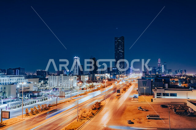 A picture of a highway to the King Abdullah Financial District (CAFD) in Riyadh, Saudi Arabia, Riyadh city towers, tourism in Saudi Arabia, car traffic on the highway in night mode, evening shot of Riyadh landmarks