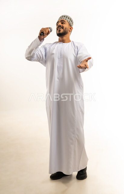 ممارسة موهبة الغناء, إلقاء المحاضرات وإقامة الندوات, العمل في تقديم الفقرات و البرامج الفنية الترفيهية, بورتريه لشاب عربي خليجي عماني يرتدي الدشداشة و الكمة يمسك بيده المايكروفون بإيماءات تدل على الحماس و الاستمتاع، الجسم بالطول الكامل, خلفية بيضاء