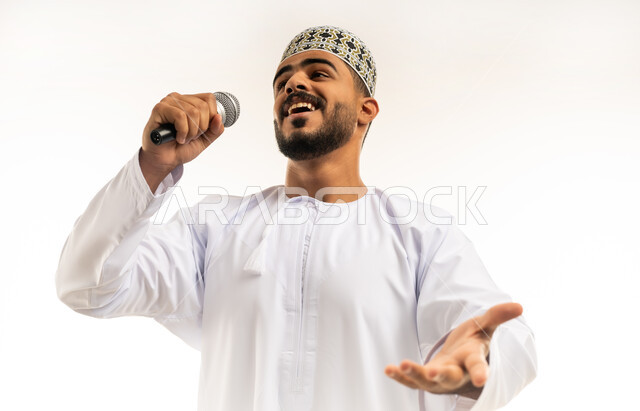إلقاء المحاضرات وإقامة الندوات, العمل في تقديم الفقرات و البرامج الفنية الترفيهية, ممارسة موهبة الغناء, بورتريه مقرب لشاب عربي خليجي عماني يرتدي الدشداشة و الكمة يمسك بيده المايكروفون بإيماءات تدل على الحماس و الاستمتاع، خلفية بيضاء