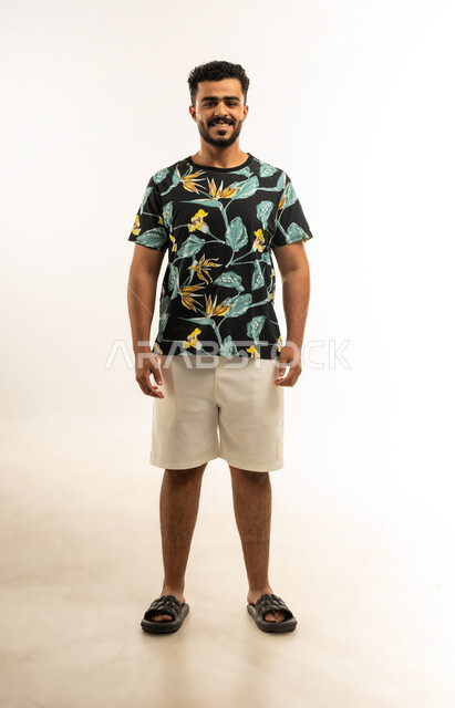 مفهوم الرجولة والثقة بالنفس، التقاط الصور الشخصية للوثائق الرسمية، بورتريه لشاب عربي خليجي عماني يرتدي الزي الكاجوال ينظر الى الكاميرا بإيماءات الثقة بالنفس, الاهتمام بالأناقة والمظهر الخارجي، صورة الجسم بالطول الكامل، خلفية بيضاء