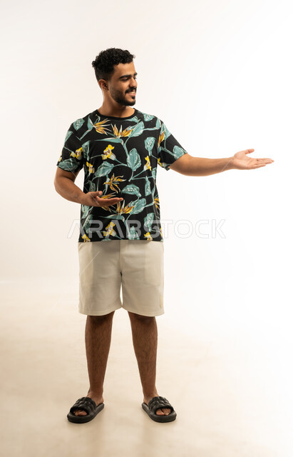 حمل ورفع شيء ما، استخدام حاسة اللمس لتحريك العناصر الهولوجراميه، بورتريه لشاب عربي خليجي عماني مبتسم يرتدي الزي الكاجوال يرفع يده للاعلى بإيماءات الترحيب، تعابير الفرح و السرور، الإشارة نحو هدف معين، صورة الجسم بالطول الكامل، خلفية بيضاء