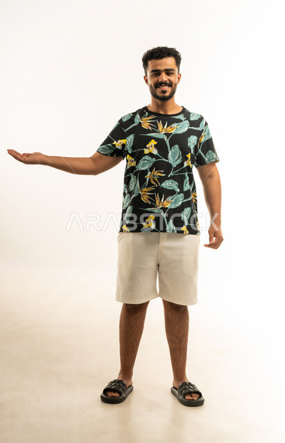 حمل ورفع شيء ما، استخدام حاسة اللمس لتحريك العناصر الهولوجراميه، بورتريه لشاب عربي خليجي عماني مبتسم يرتدي الزي الكاجوال يرفع يده للاعلى بإيماءات الترحيب، النظر الى الكاميرا بتعابير السرور، الإشارة نحو هدف معين، صورة الجسم بالطول الكامل، خلفية بيضاء