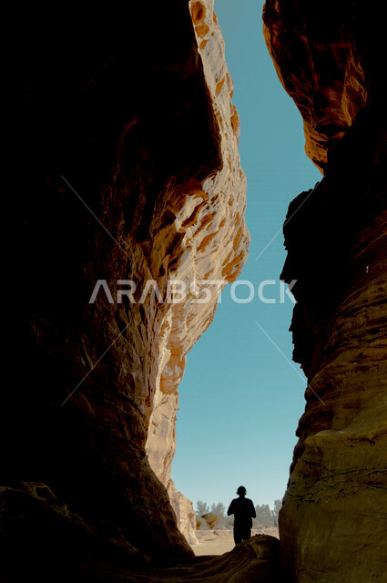 صورة ظلية لرجل بين شقي جبل، جمال التكوينات الصخرية الطبيعية في العلا بالمملكة العربية السعودية، عمارة مدائن صالح في العلا، الحضارة القديمة، معالم اثرية سياحية في السعودية