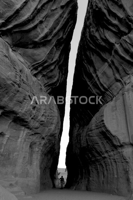 صورة ظلية لرجل بين شقي جبل، جمال التكوينات الصخرية الطبيعية في العلا بالمملكة العربية السعودية، عمارة مدائن صالح في العلا، الحضارة القديمة، معالم اثرية سياحية في السعودية