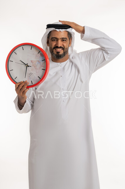 النظر الى الكاميرا باستياء و غضب، عدم انجاز المهامات في الوقت، بورتريه لرجل عربي خليجي اماراتي يرتدي الكندورة والغترة الاماراتية يحمل بيده ساعة رقمية كبيرة بإيماءات عدم الرضا، مفهوم العد التنازلي، خلفية بيضاء