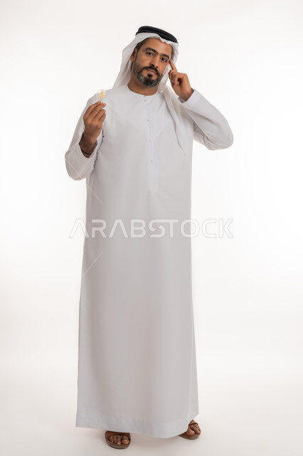 Looking at the camera with expressions of pride and self-confidence, creative development ideas, portrait of an Arab Gulf Emirati man wearing a kandura and a ghutra holding a light bulb in his hand and placing his index finger on his head with thinking gestures, the concept of the idea with innovation and inspiration, full body length, white background