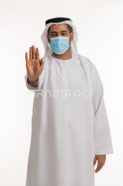 نشر الوعي الصحي للحد من انتشار الأمراض، النهي عن فعل شيء ما، اتباع إجراءات وزارة الصحة الاحترازية، أهمية تلقي التطعيم ضد فايروس كورونا، بورتريه لرجل عربي خليجي اماراتي يرتدي الكندورة والغترة الاماراتية يرفع كفه للأعلى بإيماءات الرفض وعدم الرضى والقبول، خلفية بيضاء