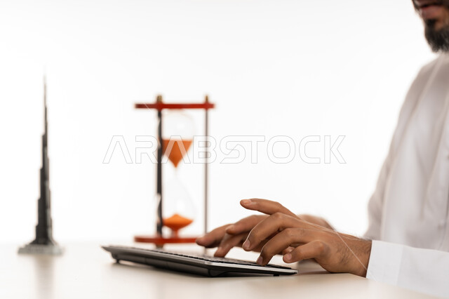 3D model of the famous Burj Khalifa with hourglass, realizing the value of time and completing tasks accurately and efficiently within the specified time, close-up portrait of an Arab Gulf Emirati man wearing a kandura typing on a keyboard, punctuality, time management and schedule concept, white background