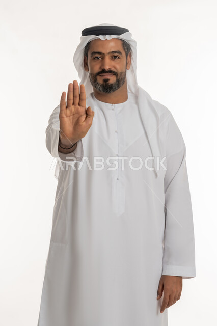 النهي عن فعل شيء ما, الصمت والتوقف عن الكلام, بورتريه لرجل عربي خليجي اماراتي يرتدي الكندورة والغترة الاماراتية يرفع كفه للأعلى بإيماءات الرفض وعدم الرضى والقبول, طلب خفض الصوت والتهديد, خلفية بيضاء