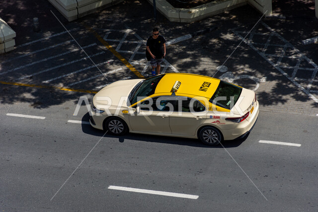 Transportation on paved asphalt roads, providing safety and comfort on the streets of the United Arab Emirates, a picture from above of a yellow taxi on the street in Dubai, interest in developing infrastructure