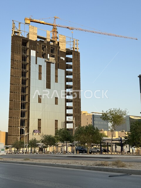 Construction of the main facade and implementation of the reconstruction plan by forming the basic structure of the building, a skyscraper under construction in the Kingdom of Saudi Arabia, heavy machinery and equipment, cranes and high scaffolding, the concept of structural and architectural engineering, a tower under construction using modern machinery