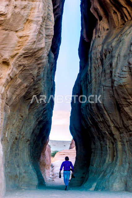 صورة لرجل بين شقي جبل، الجمال التاريخي لمدائن صالح في العلا بالمملكة العربية السعودية، الحضارة العربية القديمة، جمال التشكيلات الصخيرة، معالم اثرية سياحية في السعودية