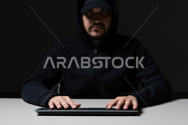 استخدم جهاز الحاسوب لأغراض غير قانونية, التسلل عبر الأمن السيبراني، قرصنة وسرقة البيانات, بورتريه مقرب لشاب عربي خليجي إماراتي يرتدي سترة سوداء يعمل في مجال الهكر, خلفية سوداء