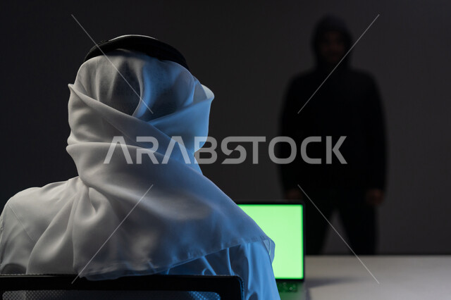 مفهوم الجرائم الالكترونية, اختراق حماية وأمن وخصوصية المستخدمين, التعرض للهجمات والاختراقات, بورتريه مقرب من الخلف لرجل عربي خليجي إماراتي يرتدي الكندورة والغترة البيضاء يعمل على جهاز الحاسوب, عرض شاشة خضراء عبر الحاسوب, كروما, خلفية سوداء