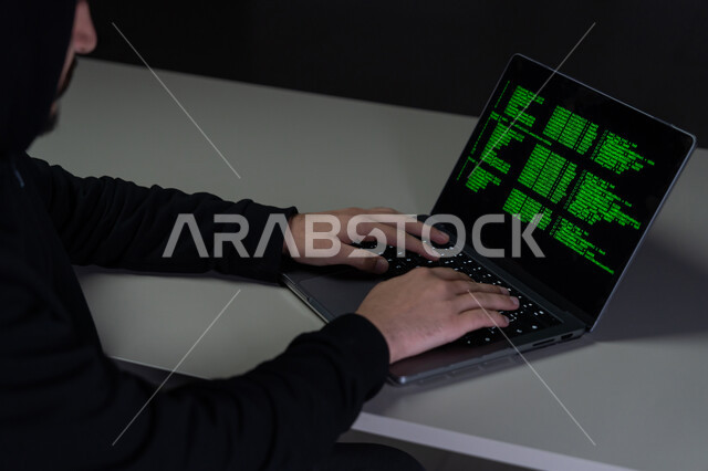 استخدام لغات البرمجة، تطوير وبناء المواقع والتطبيقات، القدرة على اختراق حماية الأجهزة ،أكواد وخوارزميات برمجية, مفهوم الجرائم الالكترونية, بورتريه مقرب من الخلف لشاب عربي خليجي إماراتي يرتدي سترة سوداء يعمل في مجال الهكر الغير قانوني, خلفية سوداء
