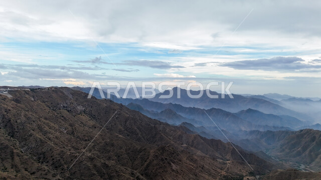 Clouds and dense clouds on the peaks, heights and high mountains, natural places for adventures and safaris, the mountainous environment of the Abha region in Asir, rocky mountain ranges, terrain on the mountain slopes