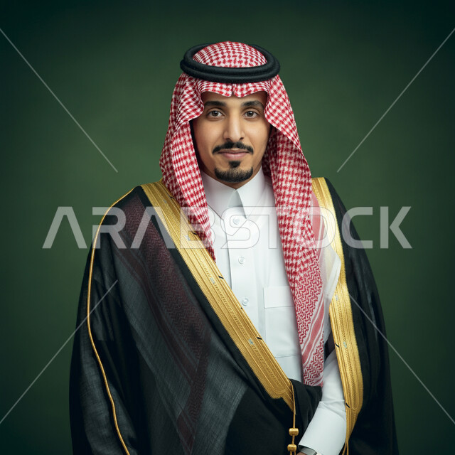 Concern for elegance and appearance, portrait of a smiling Saudi Arabian Gulf man wearing a traditional shemagh, thobe and bisht looking at the camera with gestures of pleasure, feeling self-confident, taking selfies for official documents, chroma key, green background