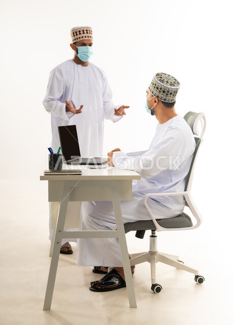 اتباع الاجراءات الوقائية لفايروس كورونا, نقاشات وحوارات عمل بين الموظفين، دمج التقنيات الحديثة في الحياة العملية, بورتريه من الجانب لشابان عربيان خليجيان عمانيان يرتديان الدشداشة والكمه والكمامة الطبية يقومان بتبادل الاحاديث، خلفية بيضاء