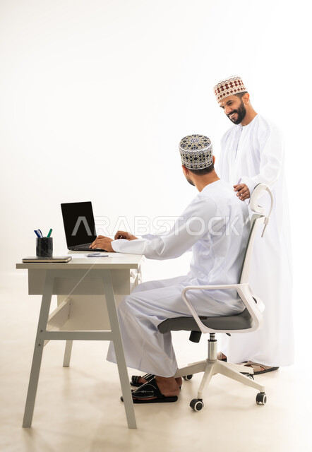 دمج التقنيات الحديثة في الحياة العملية, نقاشات وحوارات عمل بين الموظفين، بورتريه لشابان عربيان خليجيان عمانيان يرتديان الدشداشة والكمه يقومان بتبادل الاحاديث بايماءات السعادة، خلفية بيضاء