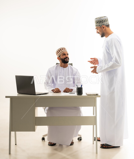نقاشات وحوارات عمل بين الموظفين، دمج التقنيات الحديثة في الحياة العملية, بورتريه لشابان عربيان خليجيان عمانيان يرتديان الدشداشة والكمه يقومان بتبادل الاحاديث بايماءات السعادة، خلفية بيضاء