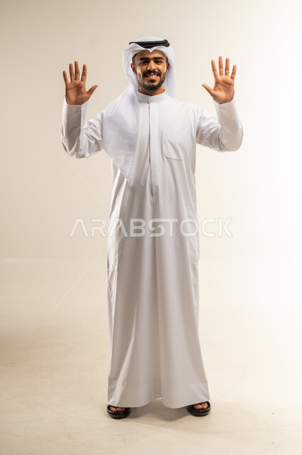 عرض باطن الكف، النظر الى الكاميرا بايماءات السعادة والسرور، بورتريه لرجل عربي خليجي كويتي يرتدي الثوب التقليدي و الغترة يرفع كفيه مفتوحة للاعلى للأعلى, صورة الجسم بالطول الكامل, خلفية بيضاء