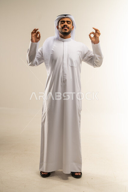 الشعور بالرضا والاستحسان، التعبير عن الإعجاب والتقدير، رفع اليدين بعلامات الجودة والقبول، الامتياز والعلامة الكاملة، بورتريه لرجل عربي خليجي كويتي مبتسم يرتدي الثوب التقليدي والغتره ينظر إلى الكاميرا بإيماءات السعادة والسرور، الجسم بالطول الكامل، خلفية بيضاء